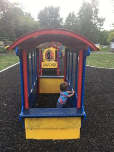 A child playing on the train structure in the park.