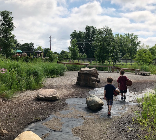 Two boys walking through the creek.