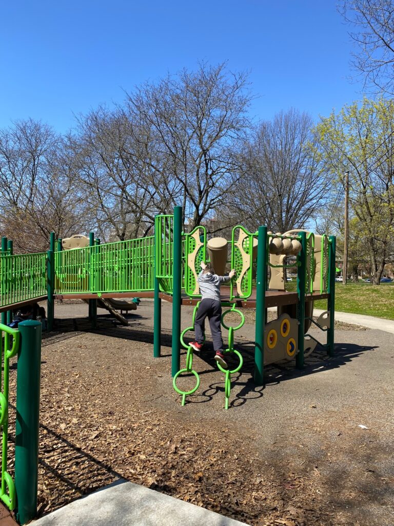 A boy climbing on circular steps to the play structure.