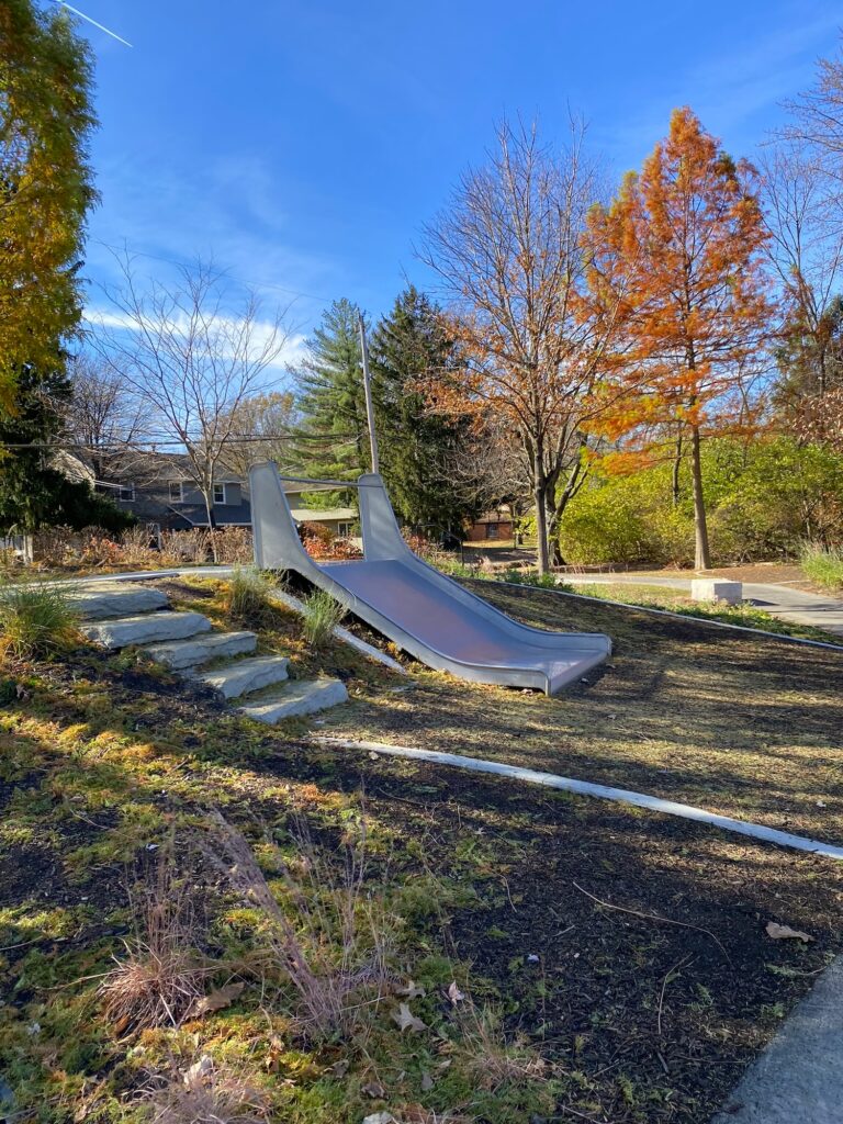 A slide built into the side of a hill at the playground.