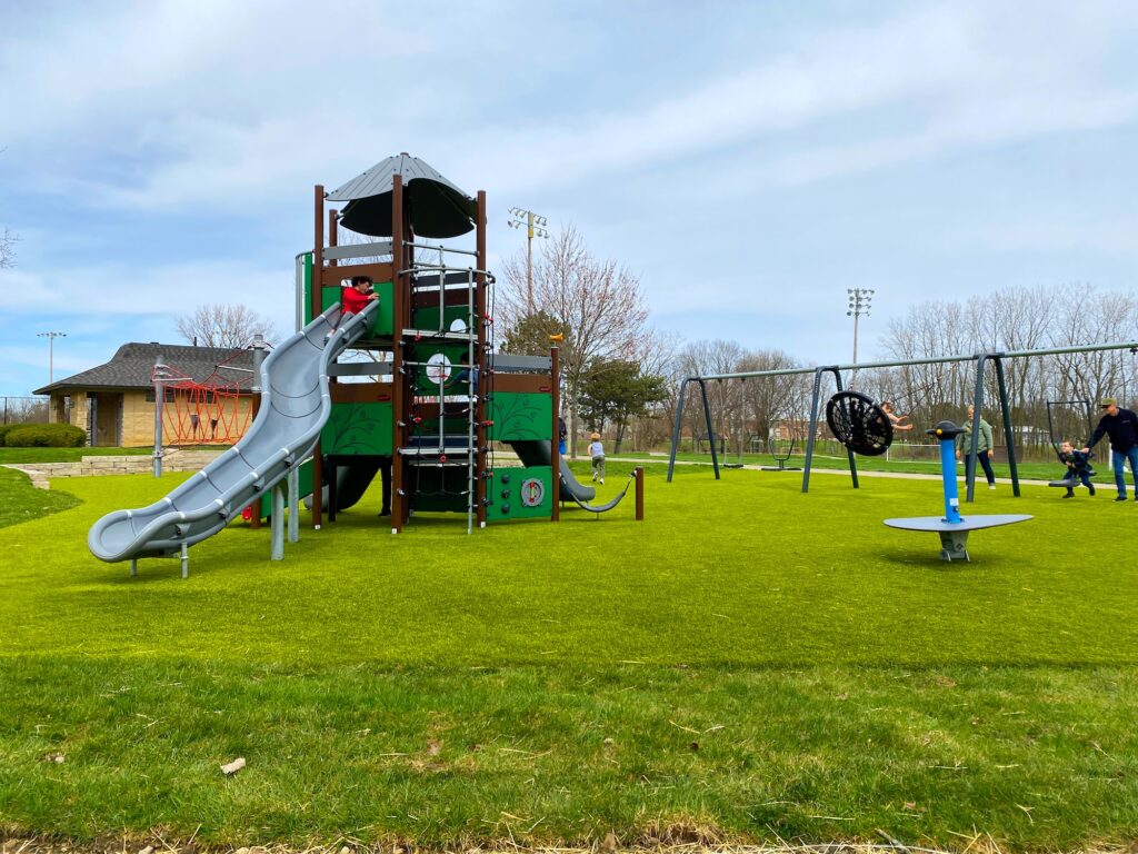 A wide-angle view of Perry Park including the large play structure and kids on the swings.