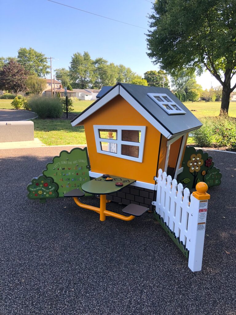 An orange house with a white fence and toddler play elements.