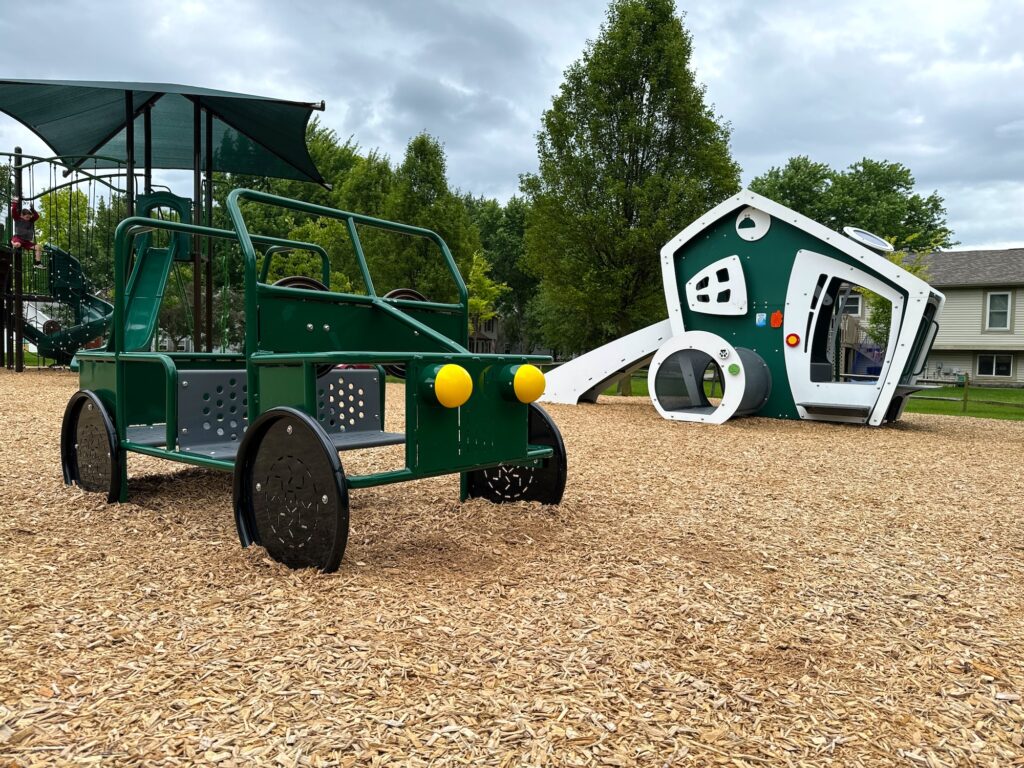A play jeep and a small playhouse for toddlers at the park.
