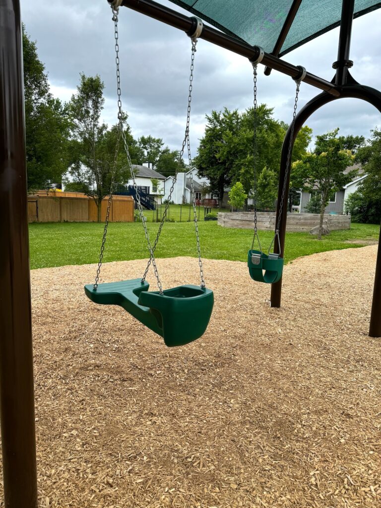 A face-to-face swing and a toddler swing at the park.